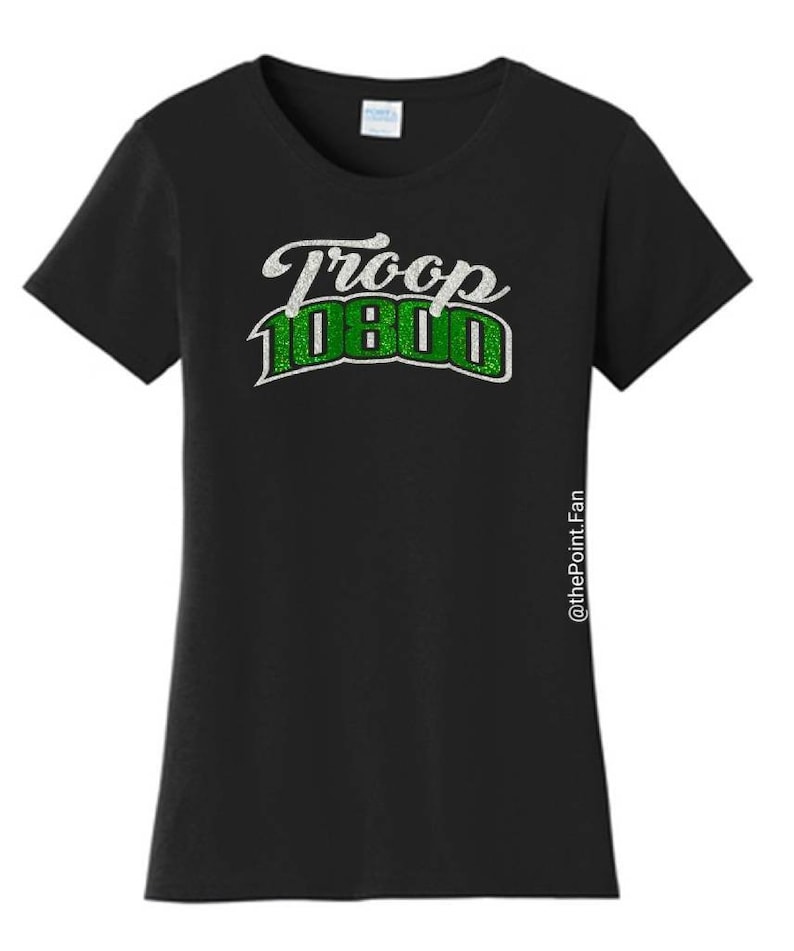 Puede incluir: Camiseta negra con un dise&ntilde;o de purpurina blanco y verde que dice "Troop 1080".