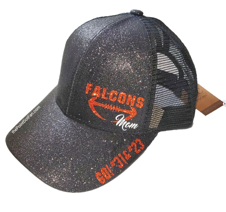 May include: Black glitter baseball cap with a mesh back. The cap features the text "Falcons Mom" in orange and white, along with "GO! 316'23" in orange. The website "thePointDotFan.com" is printed on the side.