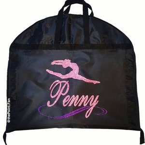Può includere: Borsa per abiti nera con un design di una ginnasta in glitter rosa e viola e il nome "Penny".