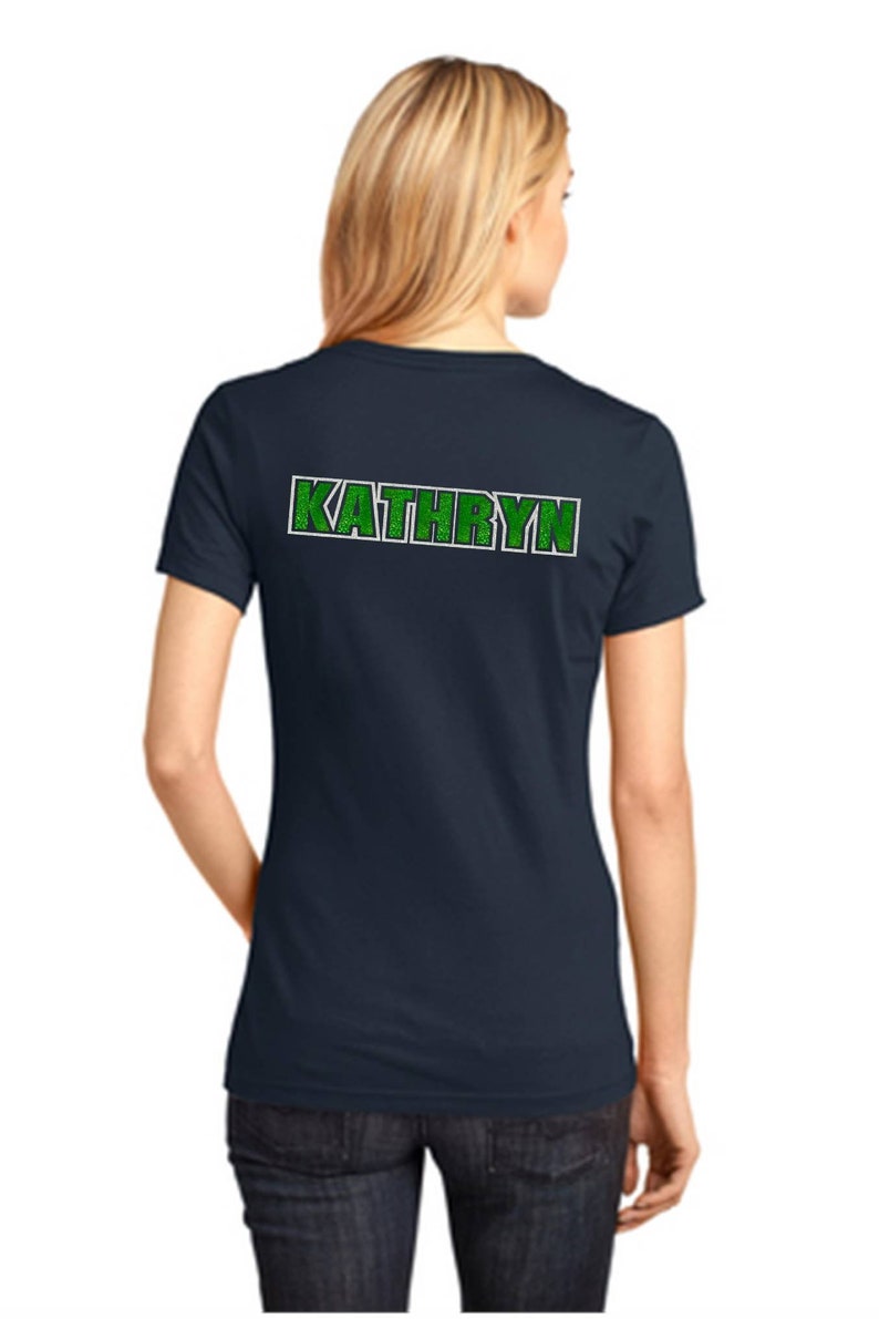 K&ouml;nnte beinhalten: Ein marineblaues T-Shirt mit einem gr&uuml;nen und wei&szlig;en "KATHRYN"-Design auf der R&uuml;ckseite.