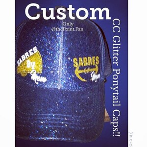 Pu&ograve; includere: Un cappello per coda di cavallo blu e oro con glitter con il testo "SABRES BY" sul lato sinistro e "SABRES" sul lato destro. Il cappello &egrave; fatto su misura ed &egrave; disponibile presso @thePoint.Fan. CC Glitter Ponytail Caps! #PIC-C