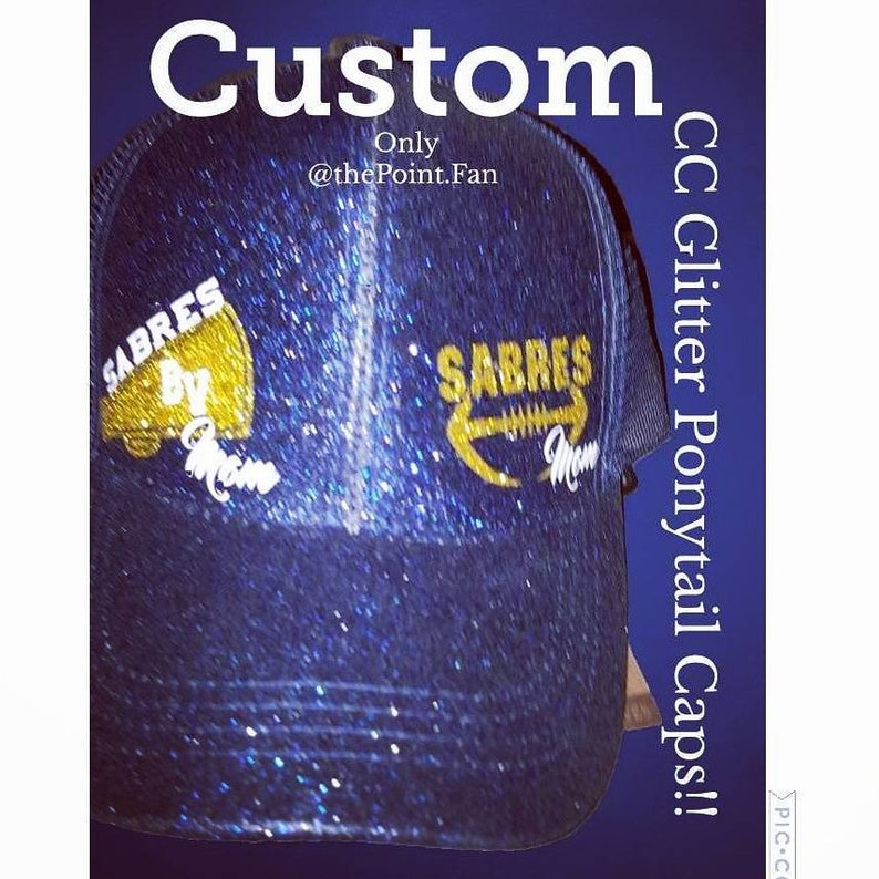 Pu&ograve; includere: Un cappello per coda di cavallo blu e oro con glitter con il testo "SABRES BY" sul lato sinistro e "SABRES" sul lato destro. Il cappello &egrave; fatto su misura ed &egrave; disponibile presso @thePoint.Fan. CC Glitter Ponytail Caps! #PIC-C
