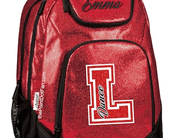 May include: Red glitter dance backpack with a black zipper and a black mesh pocket. The backpack has a large red letter "L" with the word "Dance" written inside. The name "Emma" is written on the top pocket.