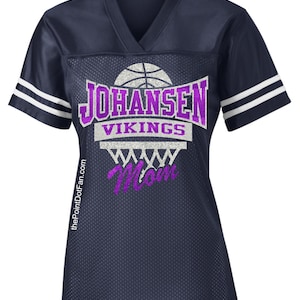 Può includere: Una maglia da basket blu navy con strisce bianche sulle maniche. La maglia presenta un design glitterato viola con il testo "Johansen Vikings" e un canestro da basket con la parola "Mamma" all'interno.