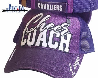 May include: A purple glitter trucker hat with the words "Cheer Coach" in white script. The hat has a mesh back and a curved brim. The word "Cavaliers" is on the back, and the name "Longo" is on the side.