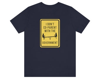 May include: A navy blue t-shirt with a yellow road sign that says "I don't co-parent with the government". The sign has a black silhouette of two children on a seesaw.