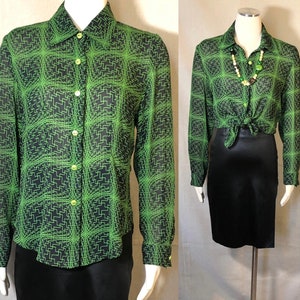 Puede incluir: Una camisa de manga larga con botones de color negro y verde con un patrón geométrico. La camisa está hecha de una tela transparente y tiene un cuello.