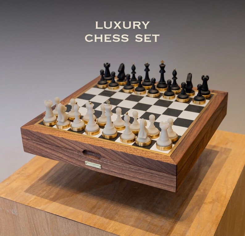 Op de afbeelding: Een luxe schaakset met zwarte en witte stukken op een schaakbord met ruitjes. De set zit in een houten kist met gouden accenten en de tekst "LUXURY CHESS SET". De schaakstukken zijn zwart en wit.