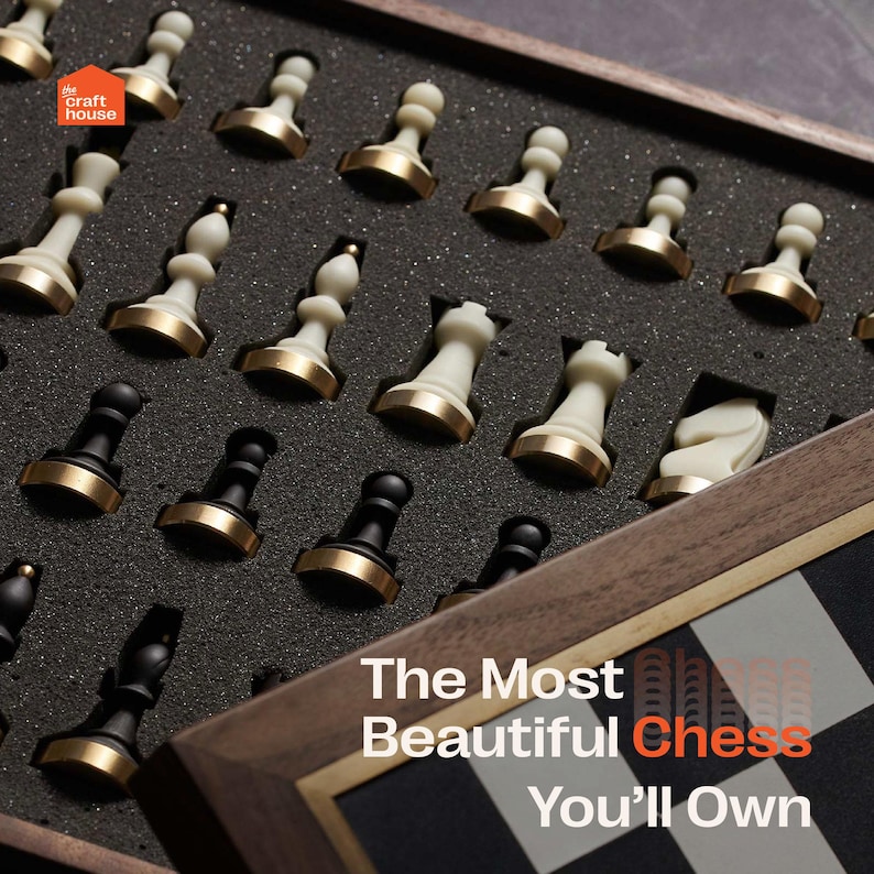 Op de afbeelding: Een houten schaakset met zwarte en witte stukken, sommige met goudkleurige bases, gerangschikt in een met schuim gevoerde doos. De tekst "The Most Beautiful Chess You'll Own" is zichtbaar.