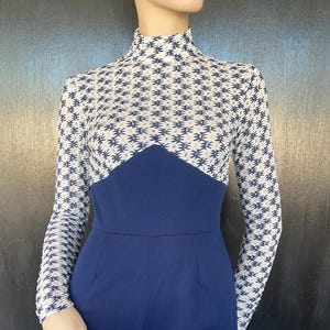 Könnte beinhalten: Ein Vintage-Jumpsuit in Marineblau und Weiß. Das Oberteil hat einen hohen Ausschnitt und lange Ärmel mit einem weißen und marineblauen geometrischen Muster. Das Oberteil ist marineblau und die Shorts sind einfarbig marineblau.