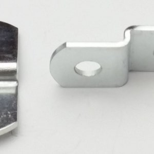May include: Two silver metal shelf brackets with two holes each. The brackets are designed to be attached to a wall or shelf.