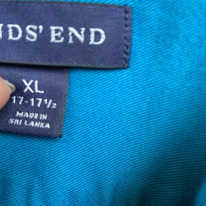 Puede incluir: Una etiqueta de camisa azul con el texto "Lands' End" e informaci&oacute;n de talla. La etiqueta dice "XL 17-17 1/2" y "Hecho en Sri Lanka".