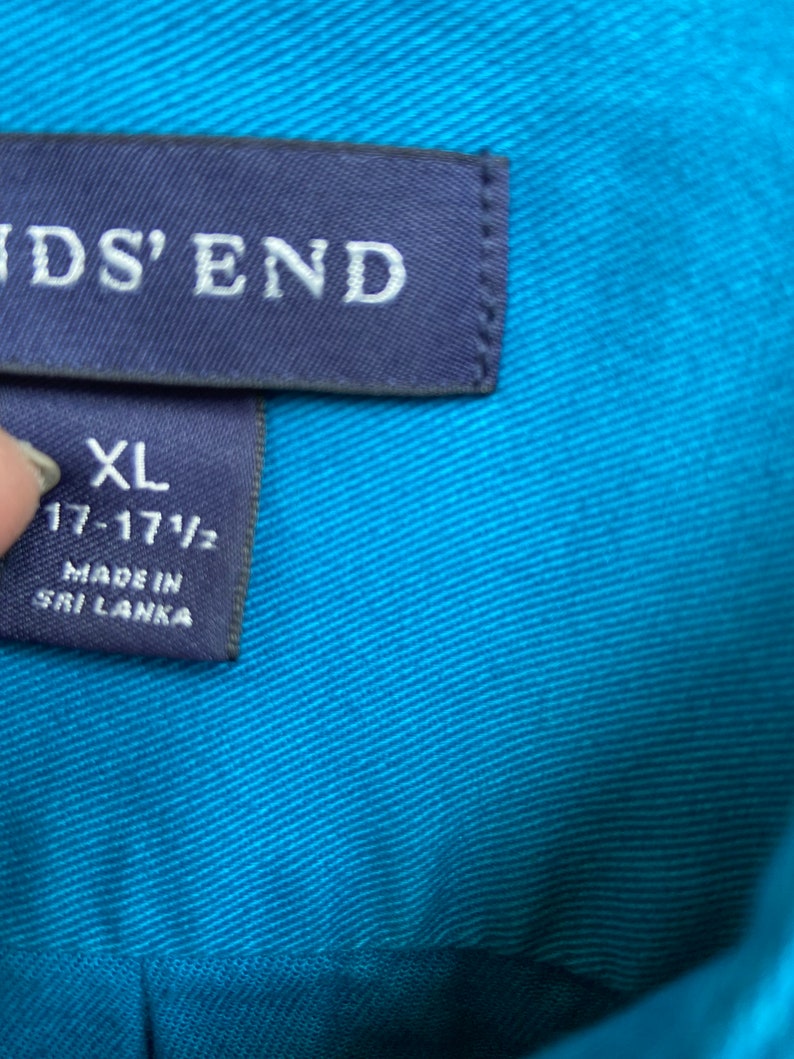 Puede incluir: Una etiqueta de camisa azul con el texto "Lands' End" e informaci&oacute;n de talla. La etiqueta dice "XL 17-17 1/2" y "Hecho en Sri Lanka".