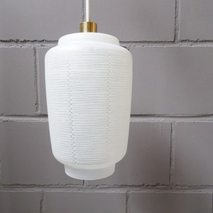 May include: White frosted glass pendant light with a brass ceiling mount. The glass shade has a textured, ribbed pattern.