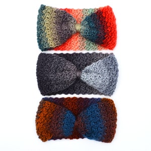 May include: Three crocheted headbands in a row, each with a bow-like design. The top headband transitions from green to red, the middle one is gray, and the bottom one shifts from brown to blue. All are set against a white background.