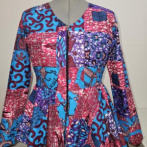 May include: A colourful patchwork jacket with a zip closure. The jacket has a blue, pink and purple pattern with a variety of floral and geometric designs.