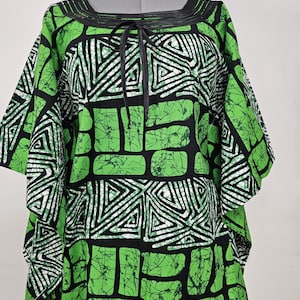 Könnte beinhalten: Ein grün-schwarzes gemustertes Kaftan mit einer schwarzen Schleife am Ausschnitt.