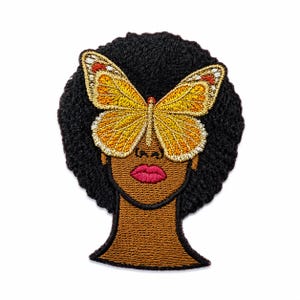 May include: An embroidered patch featuring a person with dark brown skin and a black afro hairstyle. A large, detailed butterfly with yellow, orange, and white wings is positioned over the eyes. The person has bright pink lips and a brown neck.