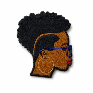 May include: An embroidered patch featuring the profile of a person with dark brown skin, a black afro hairstyle, and a faded side design. The figure wears bright blue glasses, a large gold hoop earring, and has vibrant red lips against a black border.