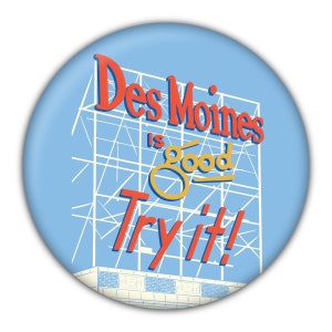 Può includere: Un bottone circolare blu e bianco con un cartello rosso e giallo che dice "Des Moines is good Try it!"