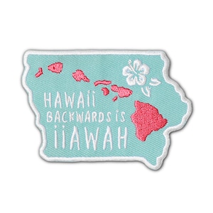 Puede incluir: Un parche bordado de color azul claro con un contorno blanco. El parche presenta un contorno rosa de las islas hawaianas y una flor de hibisco blanca. El texto "HAWAII BACKWARDS IS IIAWAH" está bordado en blanco.