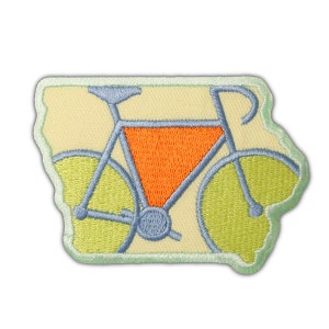 May include: A blue bicycle with orange and green accents is embroidered on a cream-colored patch in the shape of the state of Iowa.