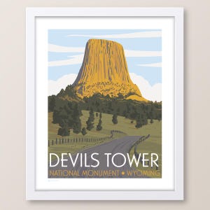 May include: A vintage-style illustration of Devils Tower National Monument in Wyoming. The image features a tall, rocky spire rising from a grassy landscape with a winding road leading towards it. The text "Devils Tower National Monument - Wyoming" is displayed below the image.