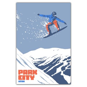 May include: A snowboarder in blue and orange clothing jumps off a snowy mountain peak against a light blue sky. The text "PARK CITY UTAH" is in the lower left corner of the image.