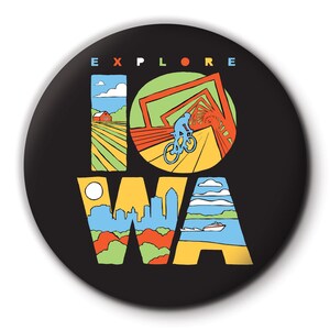Pode incluir: Um botão preto com a palavra "EXPLORE" em letras brancas acima da palavra "IOWA" em letras coloridas. As letras são preenchidas com imagens de marcos de Iowa, incluindo uma fazenda, uma ponte, um horizonte da cidade e um lago.