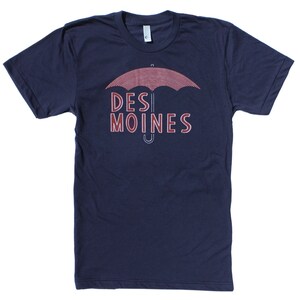 Könnte beinhalten: Ein marineblaues T-Shirt mit einem roten und weißen gestreiften Regenschirm-Motiv und dem Text "DES MOINES" in Rot.