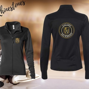 May include: Black zip-up jacket with a gold logo on the chest and back. The back of the jacket features a circular design with the text "ALL DAY, ALL KNIGHT". The jacket is displayed with hockey equipment. Text on the image reads "In Rhinestones".