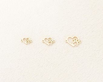 May include: Three gold-colored metal charms in the shape of hearts with paw prints inside. The charms are on a white background.