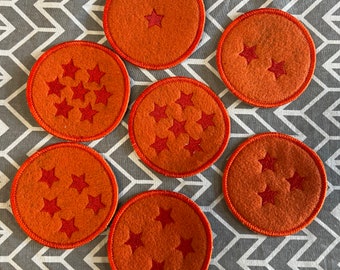 May include: Seven orange felt coasters with red embroidered stars. The coasters are round and have a raised edge. The stars are arranged in a pattern on each coaster.
