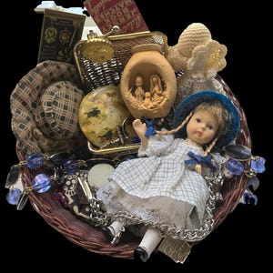 May include: A brown woven basket containing a porcelain doll in a white plaid dress and blue hat, a small terracotta nativity scene, a gold-tone mesh purse, a round decorative box with a horse print, a crochet flower, and a blue beaded necklace.
