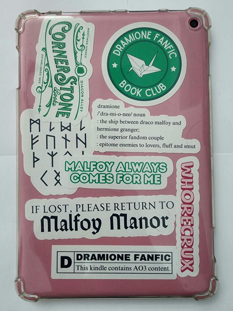 Pu&ograve; includere: Una custodia per tablet rosa con vari adesivi. Gli adesivi mostrano un logo di un club di lettura, un logo di un negozio, il nome di una coppia di fan e una citazione su un personaggio immaginario. Il testo sulla custodia recita "Dramione Fanfic This kindle contains AO3 content."