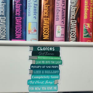 May include: A stack of teal and green books with the titles "Choices", "Just Lovers", "Lead Me Into The Light", "Mystery of the Pears", "Like a Ballast", "Completely Gone", "Art Heart. Baby!" and "For Now You Love Me".
