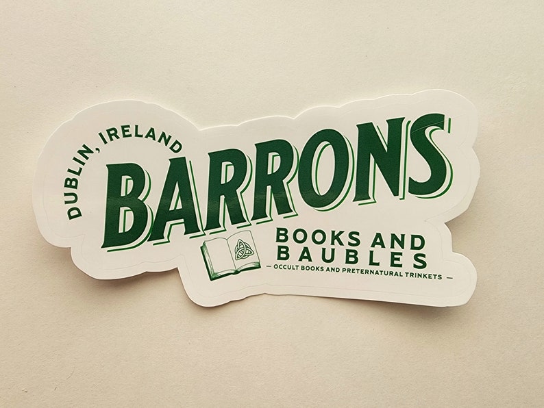 May include: A white sticker with green text that reads "Barrons Books and Baubles - Occult Books and Preternatural Trinkets - Dublin, Ireland". The sticker features a green illustration of a book with a Celtic knot.