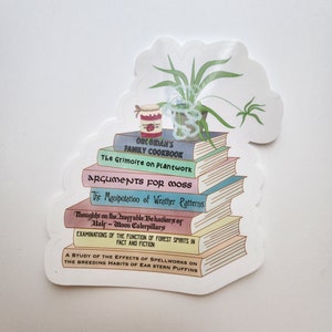 May include: A stack of colorful books with whimsical titles like "The Grimoire on Plantwork" and "Arguments for Moss". A small jar of jam and a potted plant are on top of the books.
