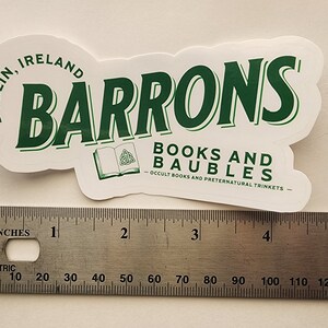 May include: A white sticker with green text that reads "Barrons Books and Baubles - Occult Books and Preternatural Trinkets - Dublin, Ireland". The sticker is about 4 inches wide.