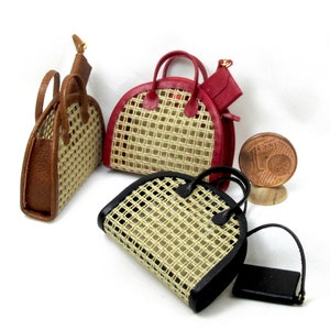 K&ouml;nnte beinhalten: Drei Miniatur-Handtaschen mit geflochtenen Stroheins&auml;tzen und Lederbesatz. Die Handtaschen sind braun, rot und schwarz.
