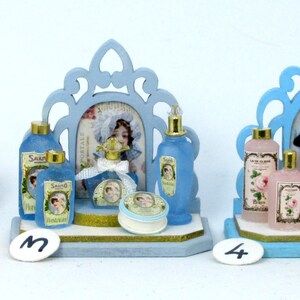 May include: Two miniature blue and white vanity sets with a mirror, bottles of perfume, and a small round container. The sets are on a white surface.