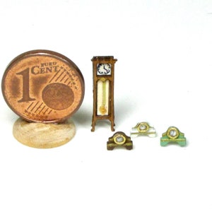 Puede incluir: Un conjunto de cuatro relojes de madera en miniatura, que incluye un reloj de pie, un reloj de chimenea y dos relojes más pequeños. Los relojes son todos de madera y tienen un aspecto vintage. El reloj de pie es el más grande y tiene un péndulo. El reloj de chimenea es más pequeño y tiene un diseño más ornamentado. Los dos relojes más pequeños son simples y tienen un aspecto más moderno.