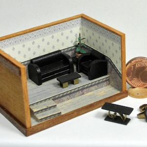 Könnte beinhalten: Ein Miniatur-Puppenhauszimmer mit schwarzen Möbeln, darunter ein Sofa, zwei Sessel und ein Couchtisch. Das Zimmer hat eine gemusterte Tapete und einen Holzboden. Das Zimmer ist etwa so groß wie eine 1-Cent-Euro-Münze.