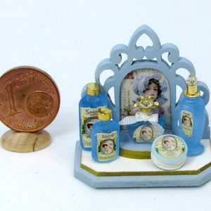 May include: A miniature blue vanity set with a mirror, four bottles of blue liquid, and a round jar of cream. The bottles and jar have labels with the word "Salvo" and a woman's face. The set is on a blue wooden base.