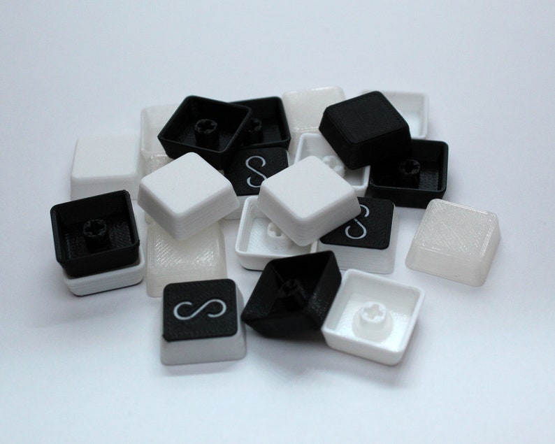 May include: A collection of black and white keycaps for a mechanical keyboard. Some keycaps feature the infinity symbol.