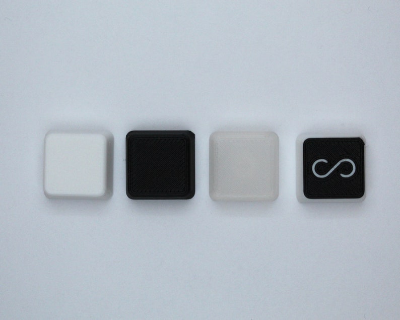 May include: Four square keys with different colors and symbols. The first key is white, the second is black, the third is light gray, and the fourth is black with a white infinity symbol.
