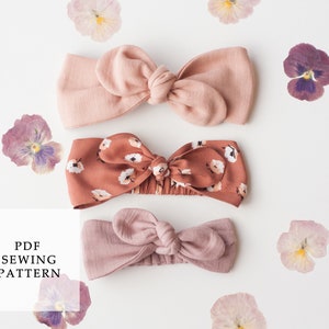 Op de afbeelding: Drie stoffen hoofdbanden met geknoopte strikken. De hoofdbanden zijn in roze en bruine tinten. Een hoofdband heeft een bloemenprint. De tekst "PDF SEWING PATTERN" staat in een wit kader.
