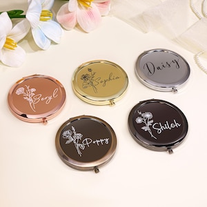 May include: An assortment of round compact mirrors in metallic finishes like rose gold, gold, and silver. Each mirror has a floral design and a name in script: Beryl, Sophia, Daisy, Shiloh, and Poppy. The mirrors are displayed on a light-coloured surface.