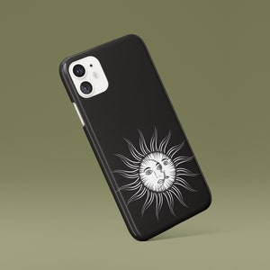 May include: Black phone case with a white sun and face design.