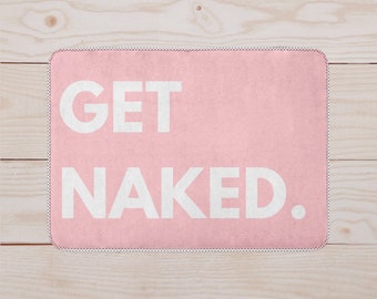 May include: A pink bath mat with the text "GET NAKED." printed in white.